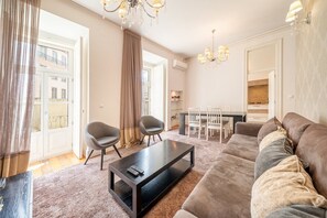 A living room with a sofa, chairs, a coffee table, and a dining area with a table and chairs. - GuestReady - Elegant Central Home with Terrace (Lisbon)