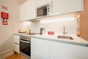 Una cucina moderna con forno a microonde, tostapane, bollitore e lavandino.