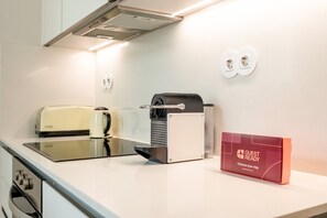Eine Küchenzeile mit Toaster, Wasserkocher, Kaffeemaschine und einem Schild mit der Aufschrift 'GUEST READY'.