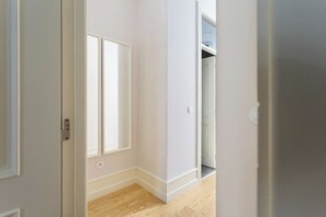 A hallway with a white door, a window, and a closet. - GuestReady - Wonderful 2BR flat in the city centre (Lisbon)