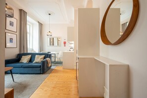 Ein modernes Hotelzimmer mit einem blauen Sofa, einem Essbereich und einem großen Spiegel.