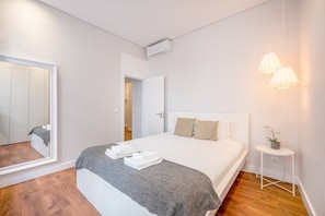 Ein modernes Schlafzimmer mit einem Bett, einem Nachttisch mit einer Lampe und einem Spiegel.