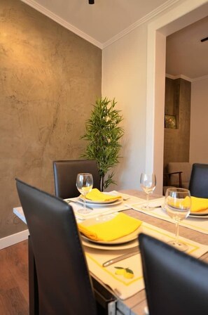 Un coin repas avec une table dressée pour quatre personnes, agrémenté de serviettes jaunes et de verres à vin.