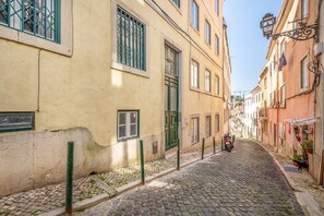Eine gepflasterte Straße, gesäumt von historischen Gebäuden mit vergitterten Fenstern, ein Roller steht am Straßenrand geparkt.