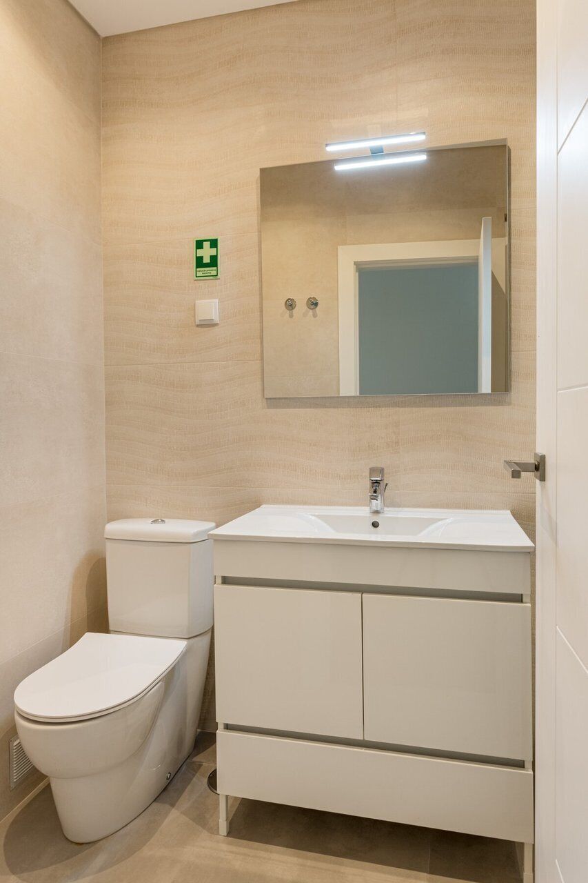 A bathroom with a toilet, sink, and mirror.