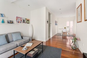 Ein modernes Wohnzimmer mit einer Couch, einem Couchtisch und einem Essbereich im Hintergrund.