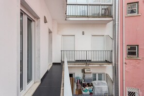 Een smalle gang met een balkon aan de rechterkant, leidend naar een deur.