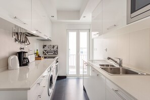 Une cuisine moderne équipée d’un lave-linge intégré, d’une machine à café et d’un évier.