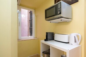 A small kitchenette with a microwave, toaster, and kettle on a white countertop. - GuestReady - Cosy studio near Santa Justa Lift (Lisbon)