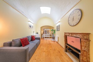 A hallway with a sofa, a fireplace, and a clock on the wall. - GuestReady - Cosy studio near Santa Justa Lift (Lisbon)