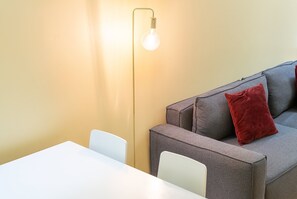 A room with a sofa, a table, and a wall-mounted light fixture. - GuestReady - Cosy studio near Santa Justa Lift (Lisbon)