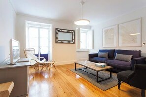 A modern living room with a sofa, coffee table, and a desk with a computer. - GuestReady - Stunning duplex near Santa Justa Lift (Lisbon)
