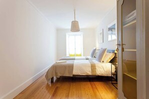 A bedroom with a bed, a window, and a hanging light fixture. - GuestReady - Stunning duplex near Santa Justa Lift (Lisbon)