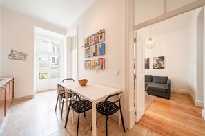 A modern living space with a dining area, a sofa, and a hallway leading to another room. - GuestReady - Chic apt near Lisbon Cathedral (Lisbon)