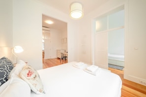 Une chambre à coucher avec un lit, des lampes de chevet, une porte donnant sur une salle de bain et une vue sur un balcon.