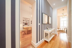 A modern interior with a striped wall, a dining area, and a hallway leading to another room. - GuestReady - Chic apt near Lisbon Cathedral (Lisbon)