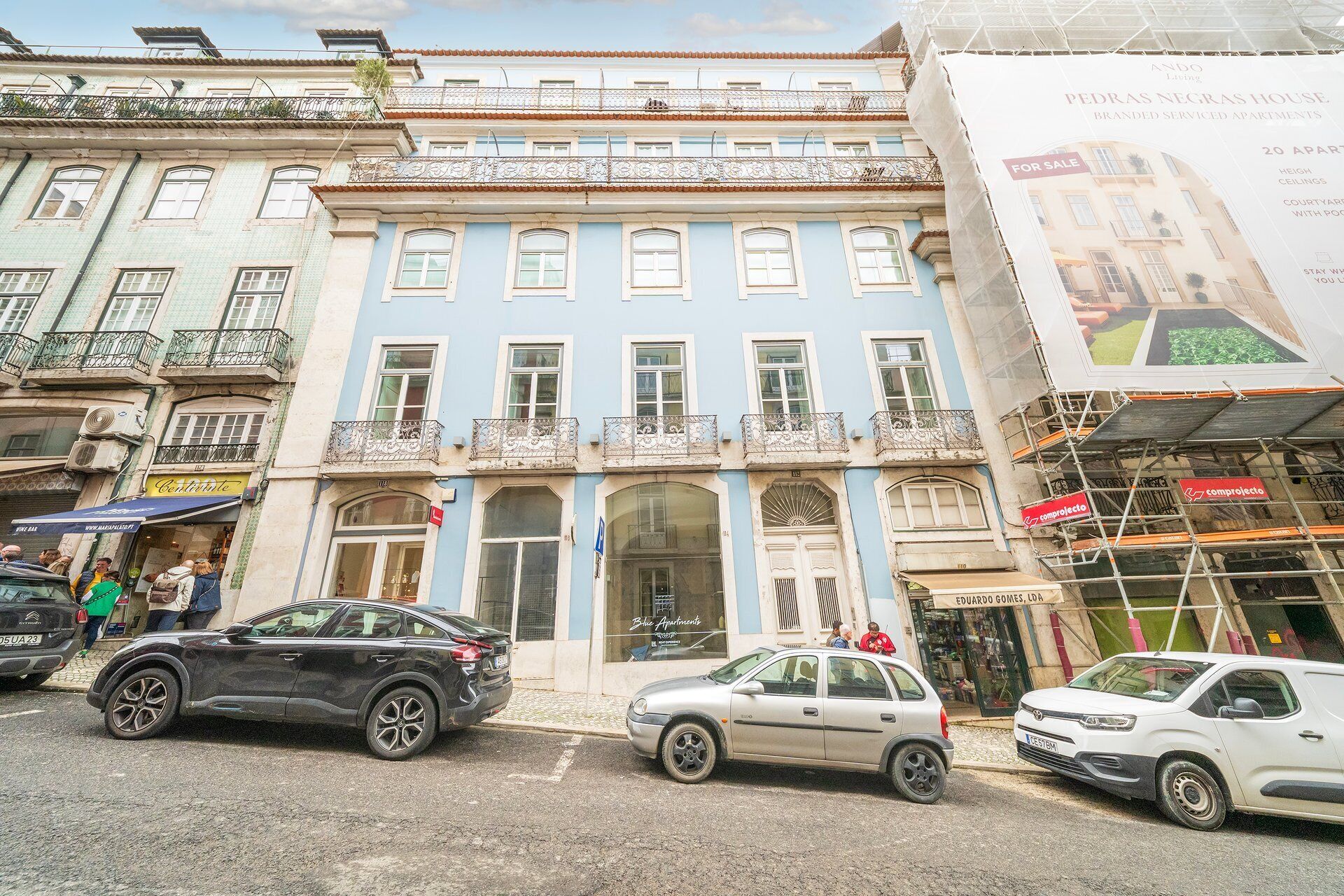 A multi-story building with a blue facade, a ground-floor shop, and a visible entrance.