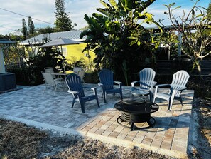 A patio area with outdoor furniture, a fire pit, and a yellow building in the background. - West Melboburne Oasis, minutes to the beach! (Melbourne)
