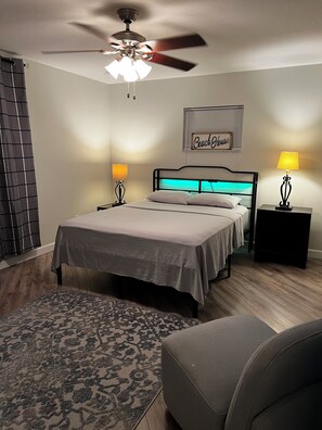 A bedroom with a bed, two bedside lamps, a ceiling fan, a rug, and a chair. - West Melboburne Oasis, minutes to the beach! (Melbourne)
