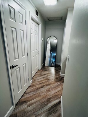 A hallway with wooden flooring, white doors, and a hallway mirror reflecting a Christmas tree. - West Melboburne Oasis, minutes to the beach! (Melbourne)
