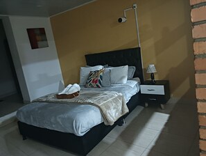 Una camera da letto con un letto, un comodino, una lampada e una telecamera di sicurezza a parete.