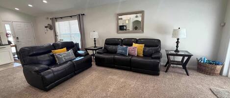 A living room with two black leather sofas, a coffee table, a lamp, and a mirror on the wall.