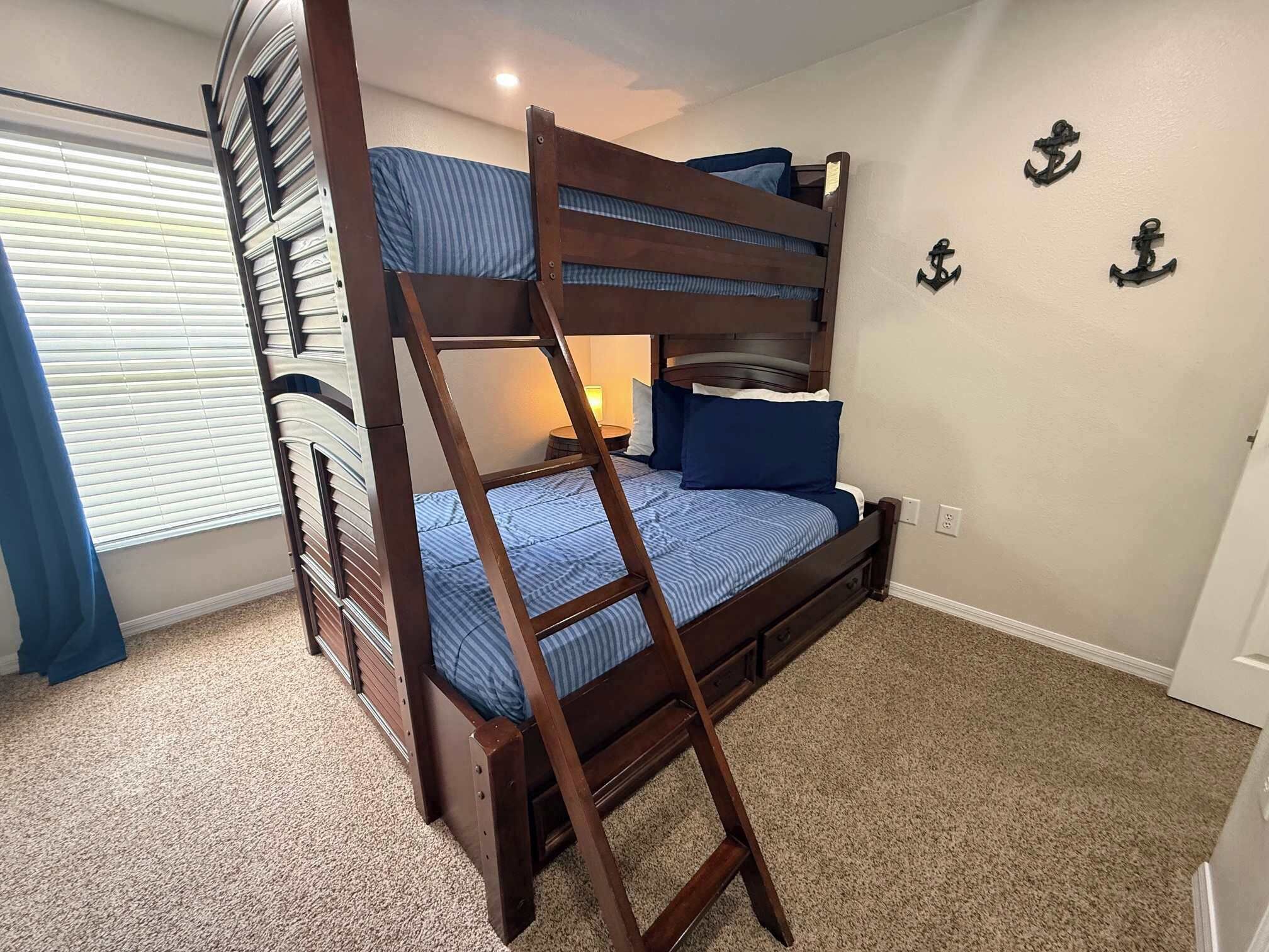 A bunk bed with a ladder, a bedside table with a lamp, and nautical-themed wall decorations.