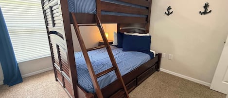 A bunk bed with a ladder, a bedside table with a lamp, and nautical-themed wall decorations.