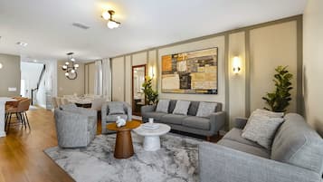 Una sala de estar moderna con un sofá, sillones, una mesa de centro y un comedor.