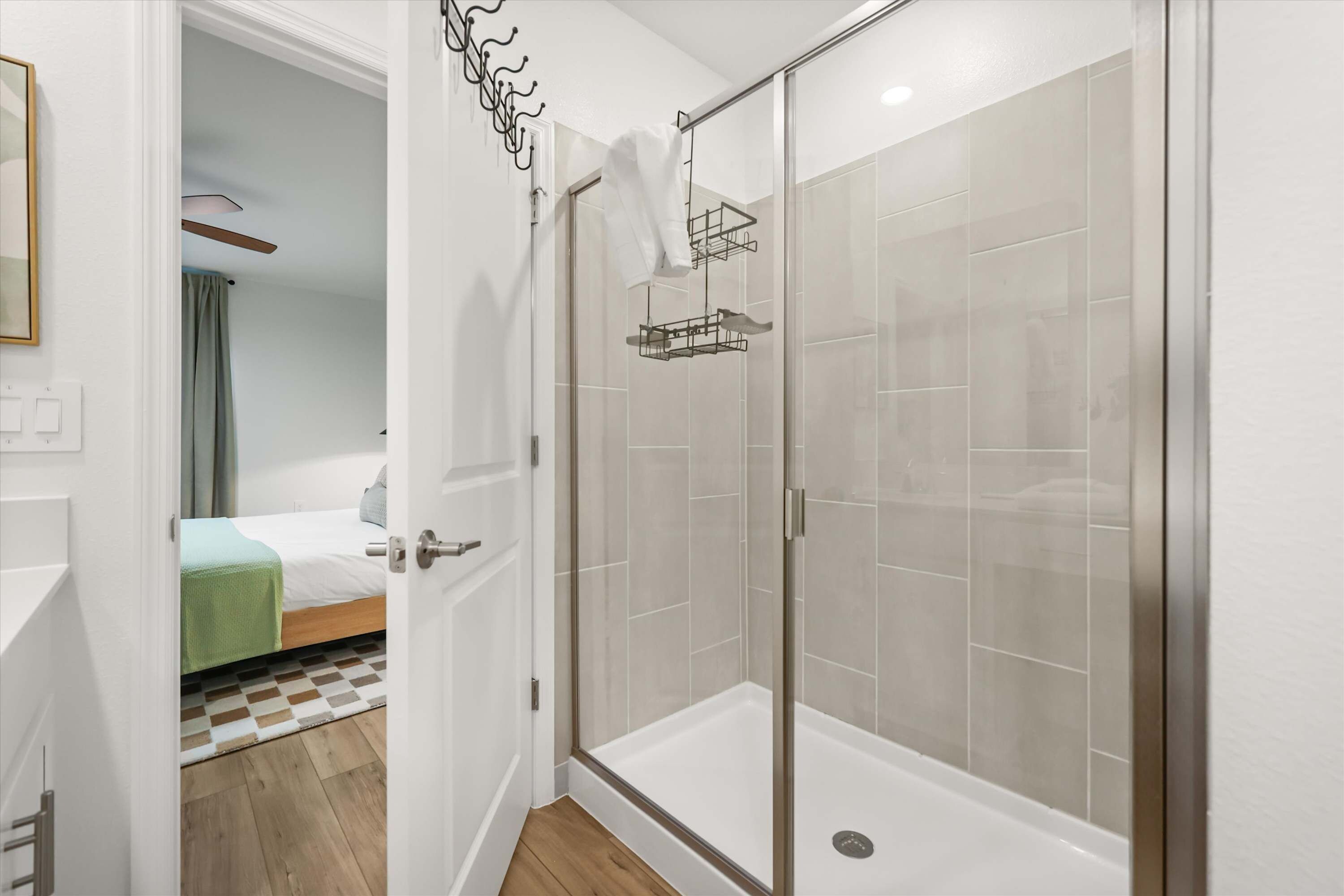 A hotel bathroom with a glass-enclosed shower, a towel rack, and a visible shower drain.