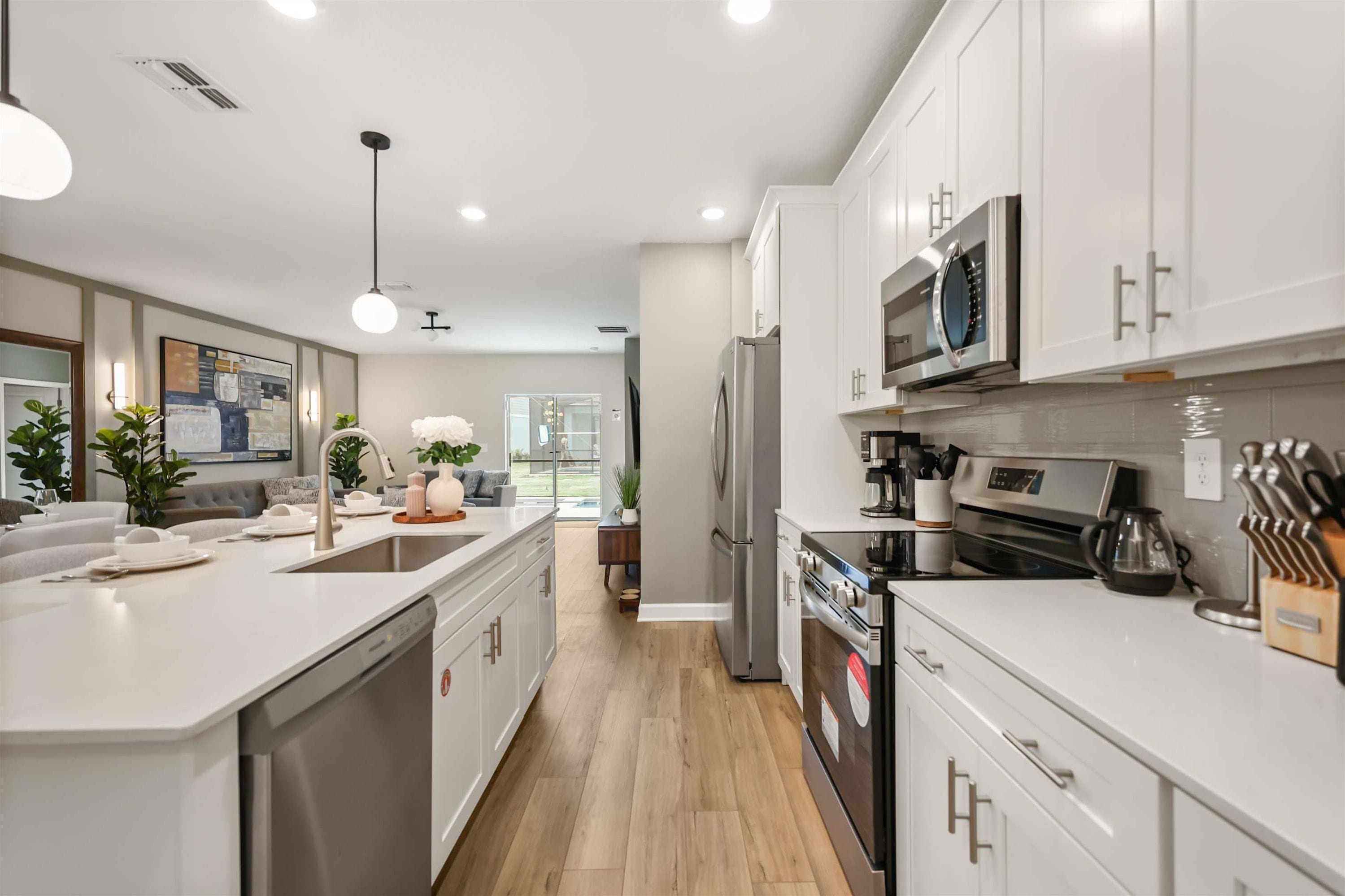 A modern kitchen with white cabinetry, stainless steel appliances, and a central island.