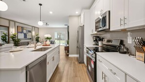 Una cocina moderna con armarios blancos, electrodomésticos de acero inoxidable y una isla central.