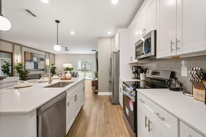 Una cocina moderna con armarios blancos, electrodomésticos de acero inoxidable y una isla central.