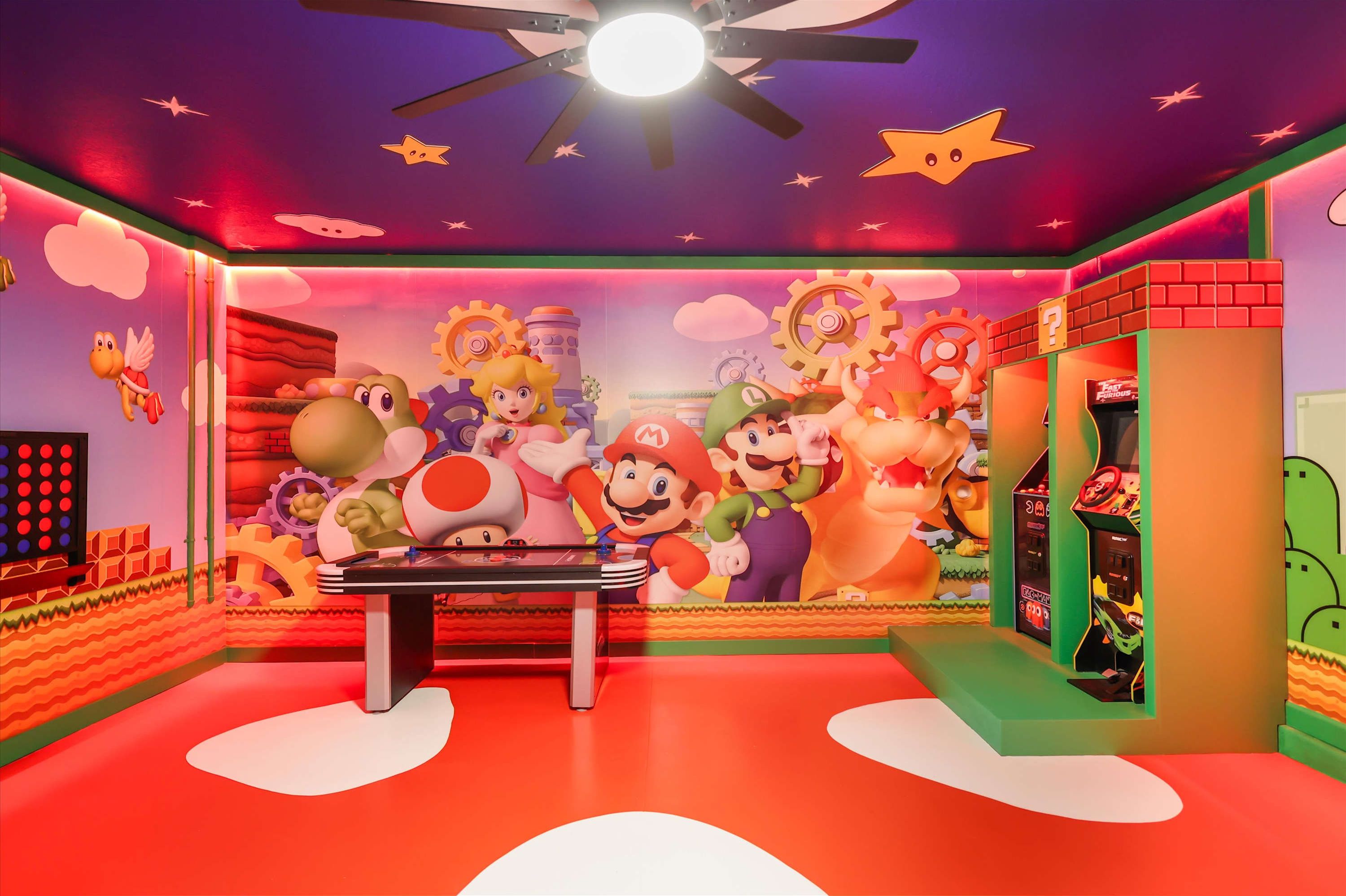 A room with a Mario-themed mural, a ceiling fan, and a Nintendo 64 gaming console.