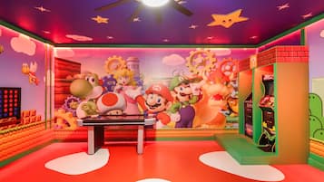 A room with a Mario-themed mural, a ceiling fan, and a Nintendo 64 gaming console.
