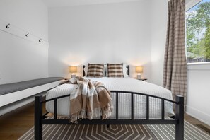 Een slaapkamer met een bed, nachtlampjes, een bankje en uitzicht op het omliggende landschap.