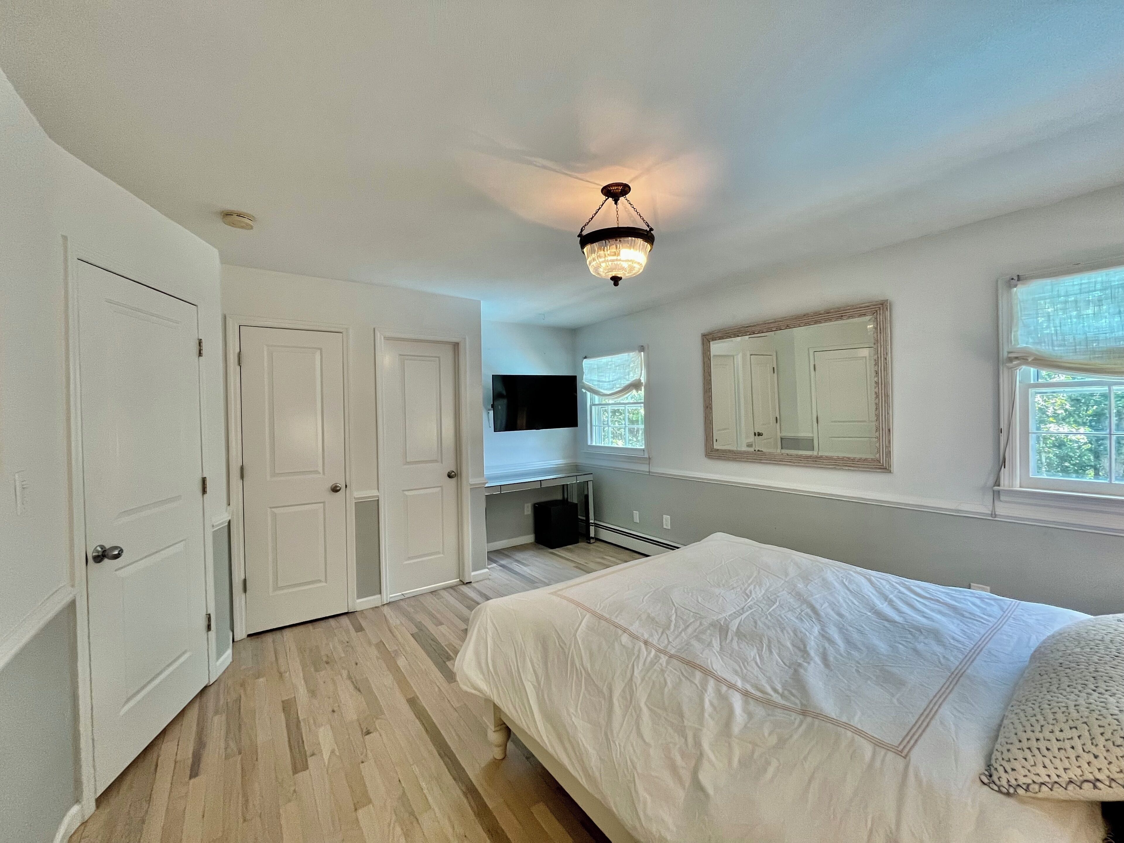 A bedroom with a bed, a dresser, a vanity, and a ceiling light.