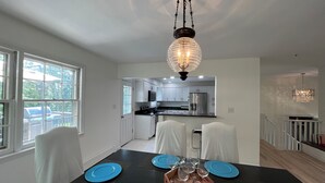 A dining area with a black table, blue plates, and white chairs.