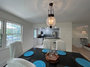 A dining area with a black table, blue plates, and white chairs.