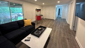 A modern living room with a black sofa, a coffee table, and a red popcorn cart.