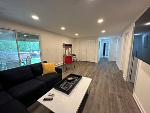A modern living room with a black sofa, a coffee table, and a red popcorn cart.