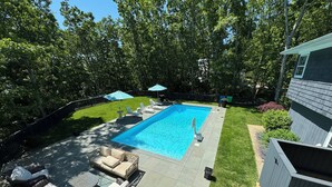 A backyard with a swimming pool, outdoor furniture, and a fenced area.