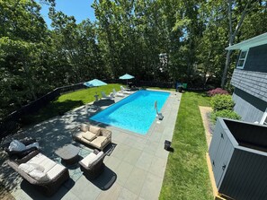A backyard with a swimming pool, outdoor furniture, and a fenced area.