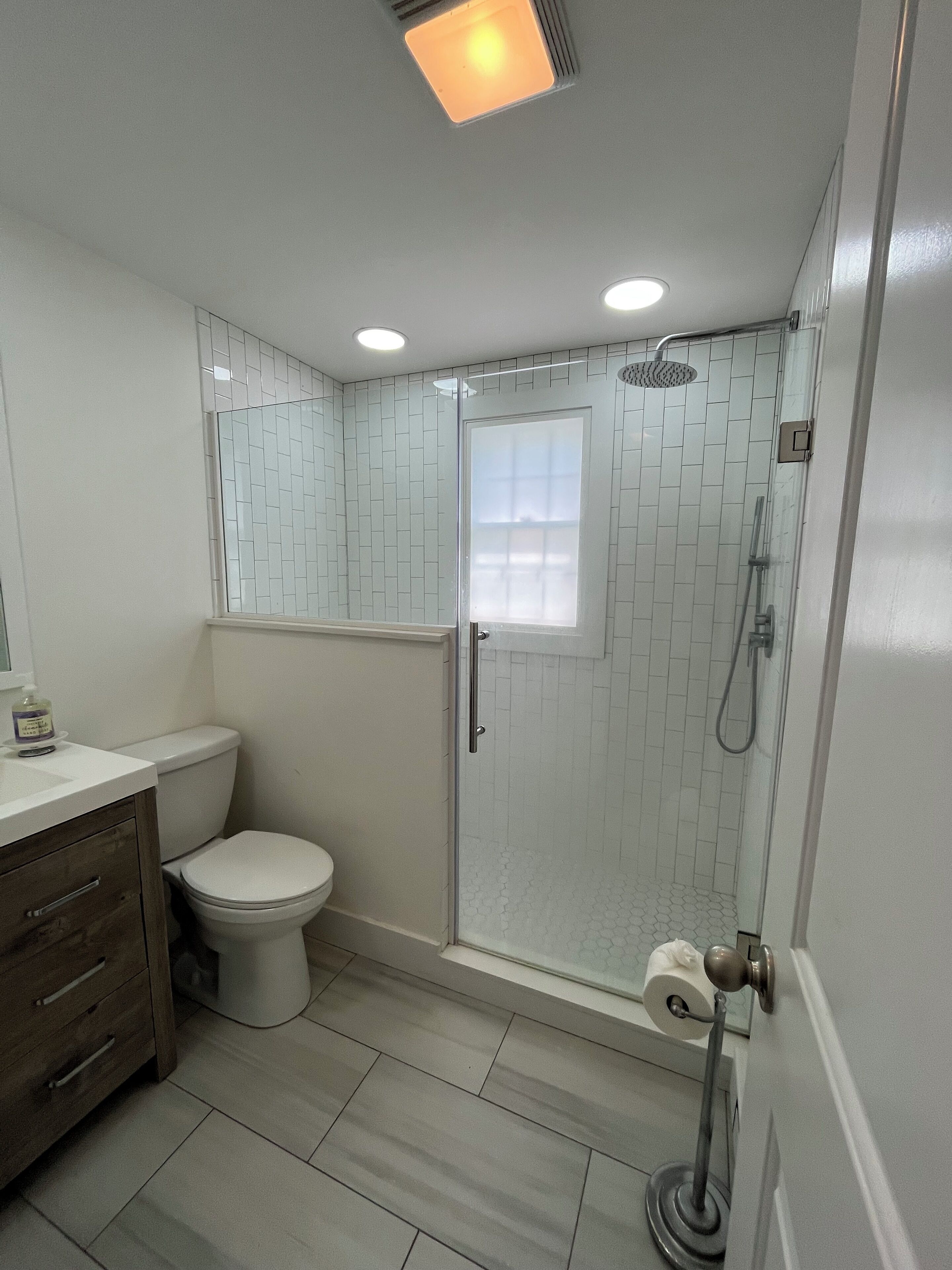 Un bagno con un WC, una doccia con porta in vetro e un lavandino con specchio.
