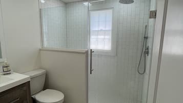 Un bagno con un WC, una doccia con porta in vetro e un lavandino con specchio.