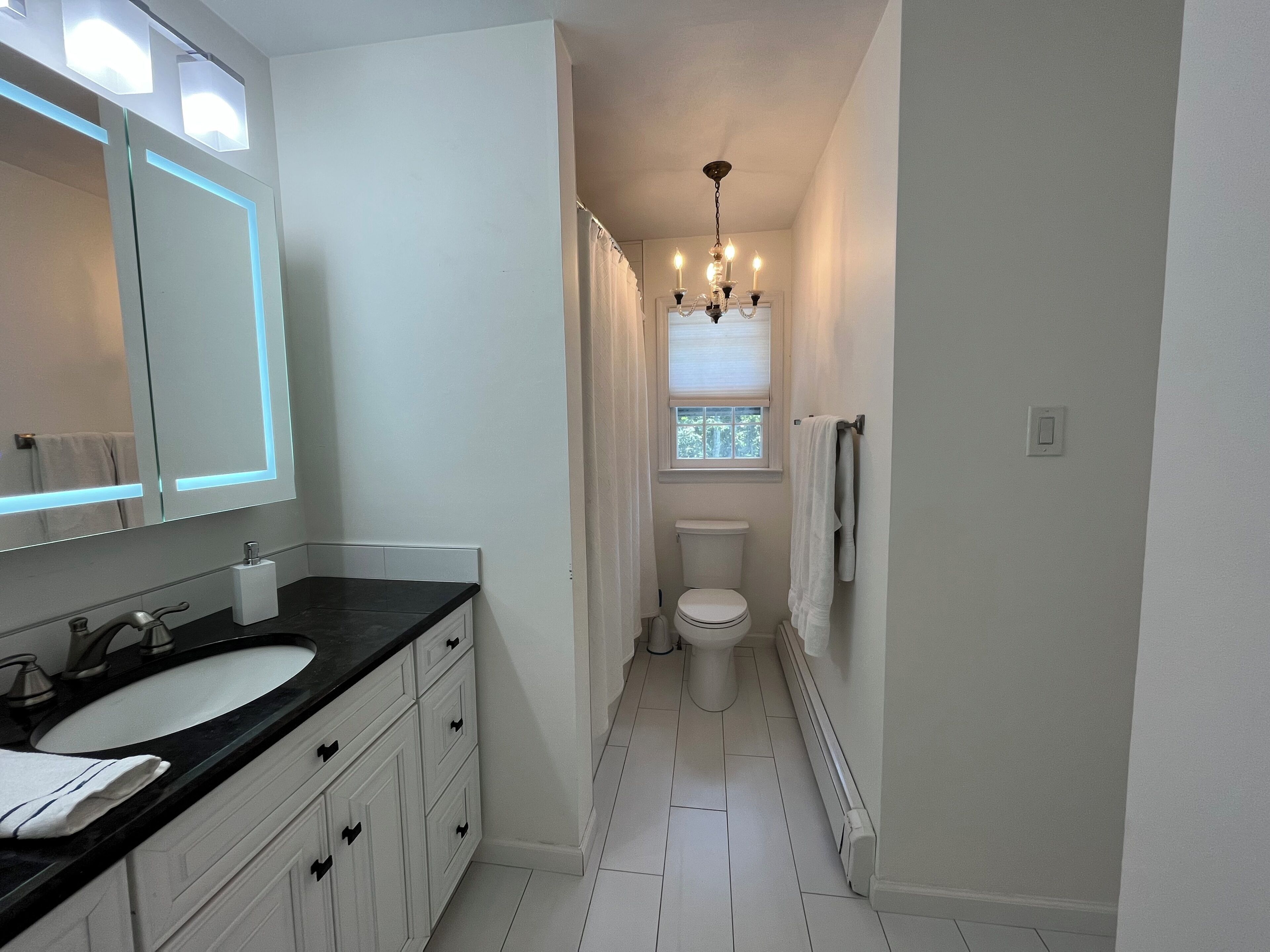 A bathroom with a white sink, vanity, and toilet.
