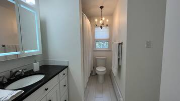 A bathroom with a white sink, vanity, and toilet.