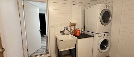 A compact laundry room with a washing machine, a dryer, and a small sink area.