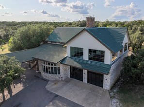 A two-story house with a stone facade, a green metal roof, and a large garage.