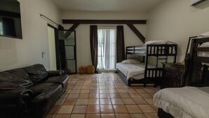 Una habitación con un sofá de cuero marrón, una cama con estructura de madera, una mesita y un espejo en la pared.